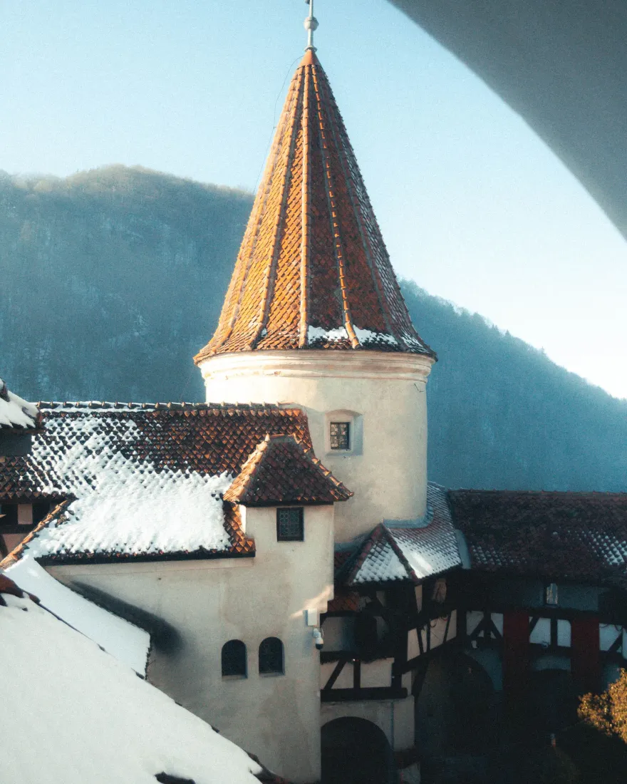 Bran Castle covered in snow, with forested mountains behind