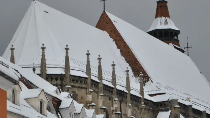 The snow-covered roof of the Black Church above the old town of Brașov in winter