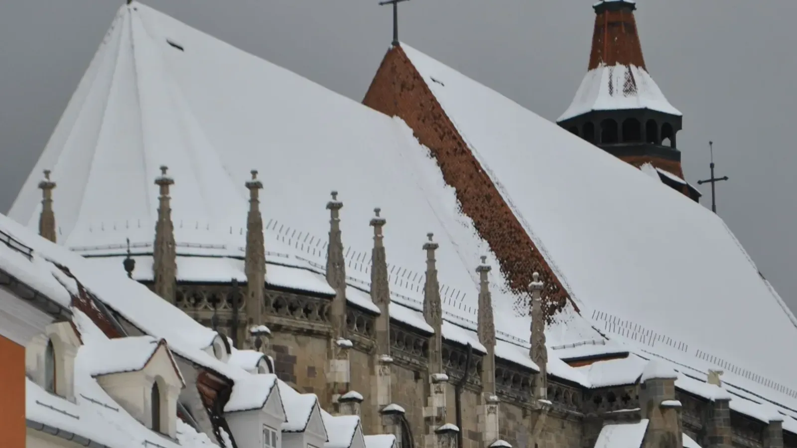 The snow-covered roof of the Black Church above the old town of Brașov in winter