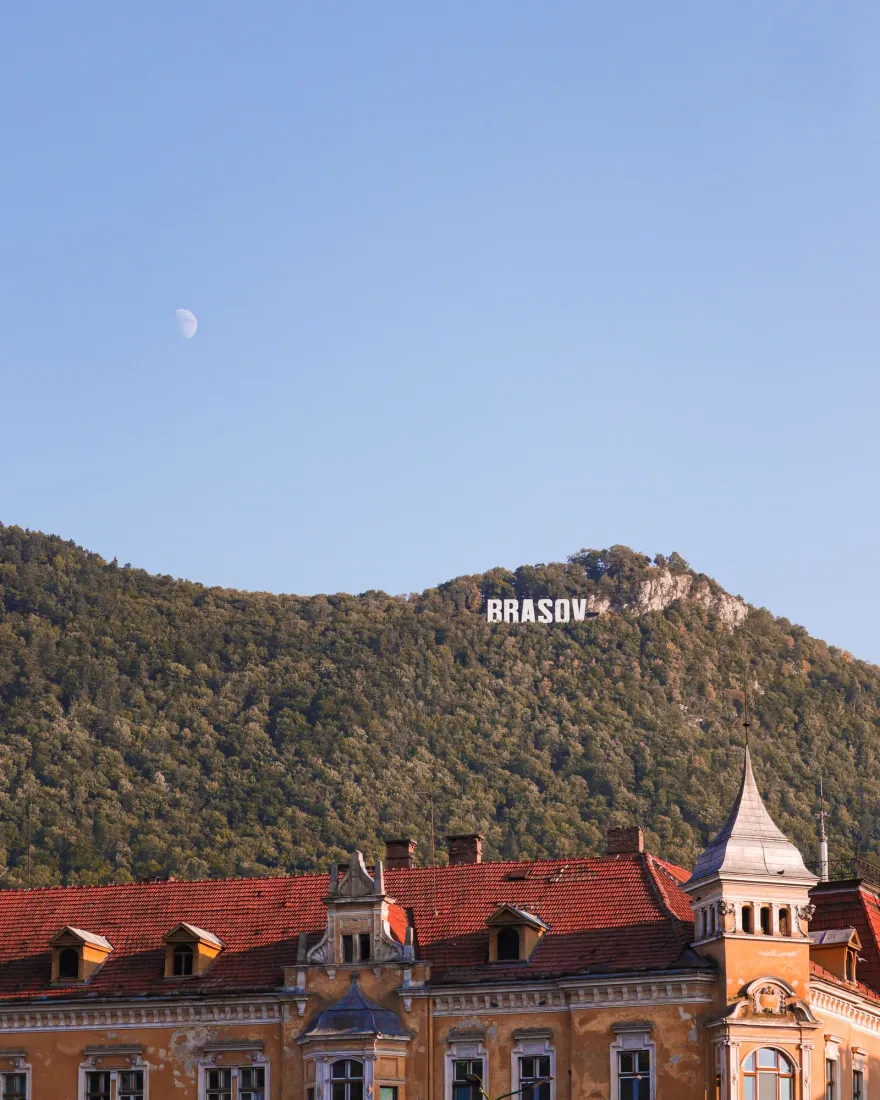 The rooftops of Brașov with Mount Tâmpa and the Brașov sign above the city