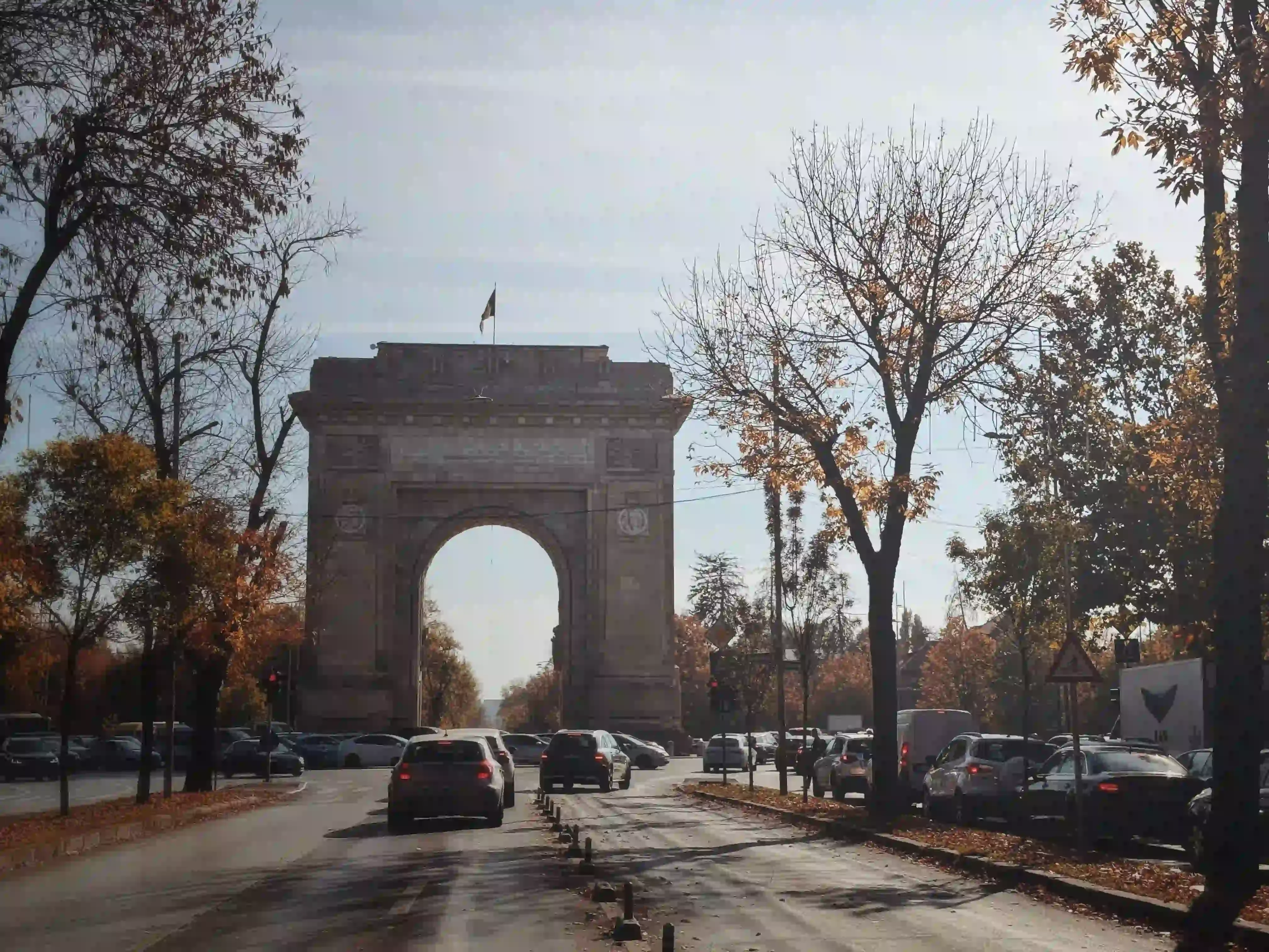 Bucharest’s Arc de Triomphe at the end of a tree-lined avenue in autumn