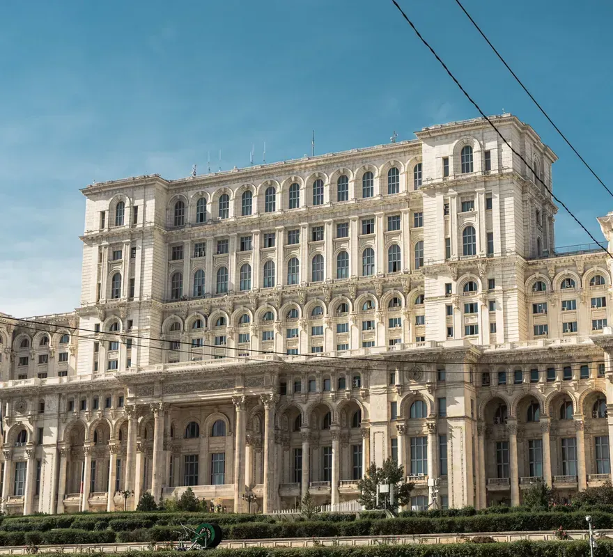 The white facade of the Palace of the Parliament in Bucharest under a blue sky