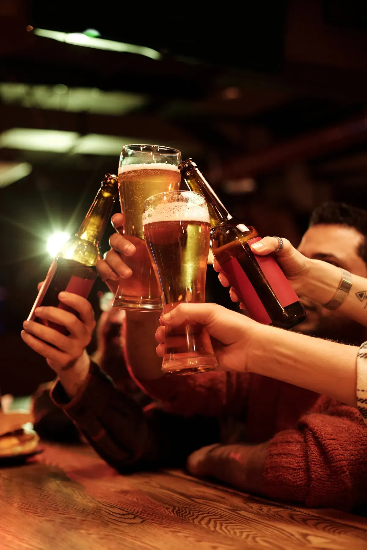 Friends toasting with glasses of beer in a dimly lit bar