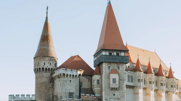 The pointed towers and red roofs of Corvin Castle in Hunedoara under a clear sky