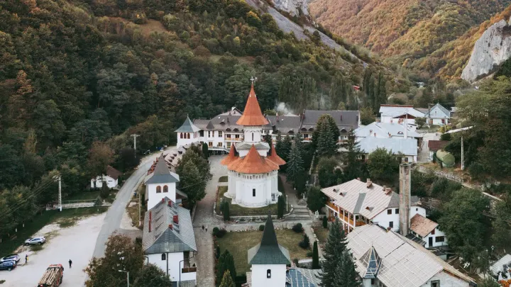 A Romanian Orthodox monastery with red domes among autumn mountains and limestone cliffs