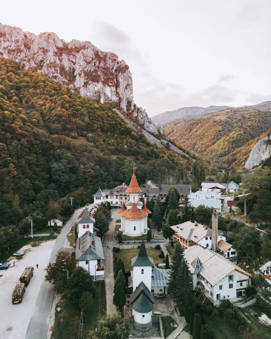 Aerial view of a Romanian Orthodox monastery with red domes in a mountain valley