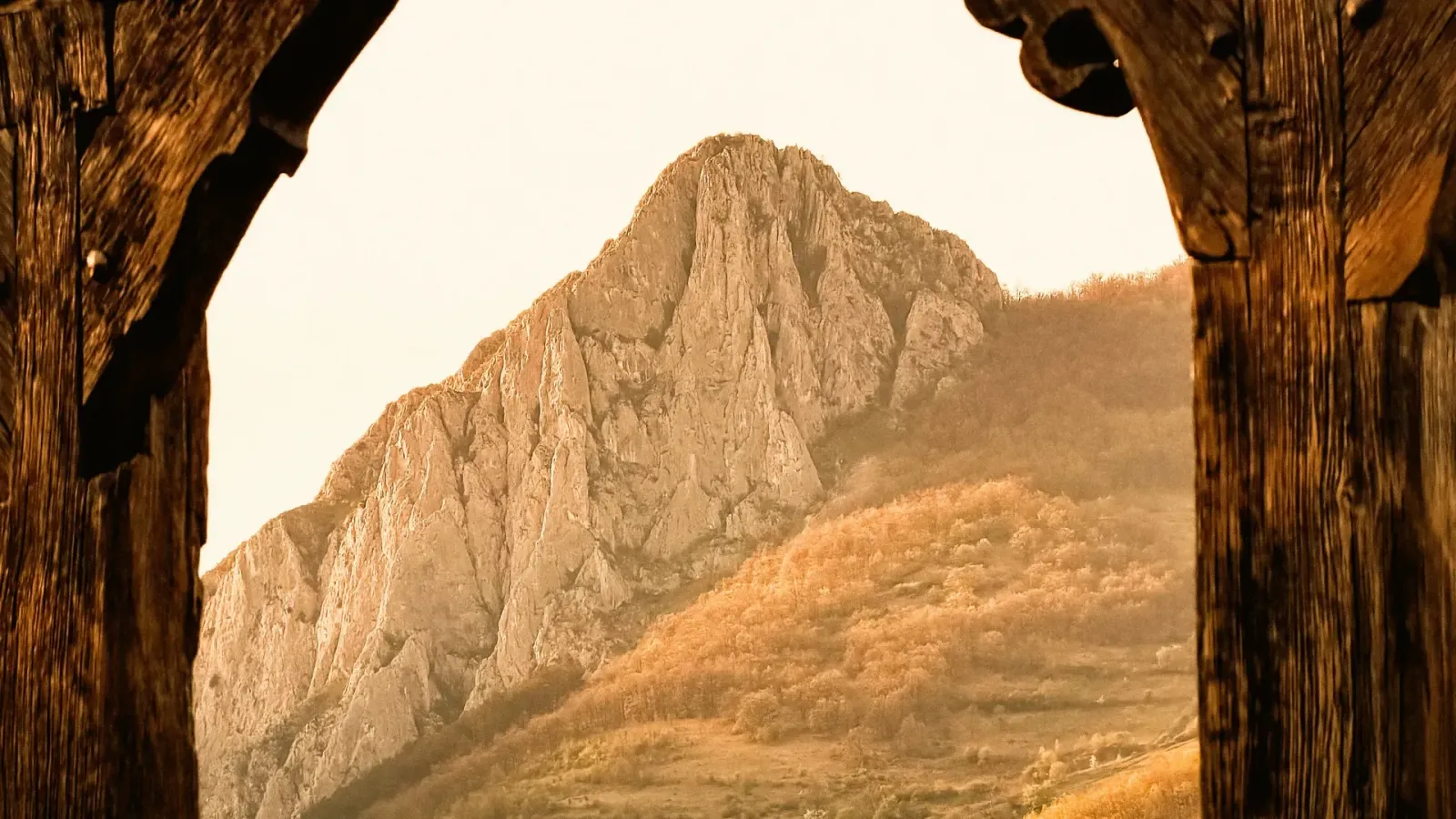 A rocky Transylvanian mountain seen through a traditional wooden gate