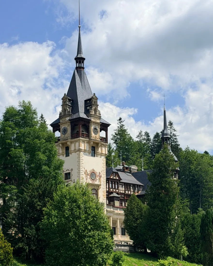 The towers of Peleș Castle in Sinaia surrounded by forest, a stop on the way to Bran