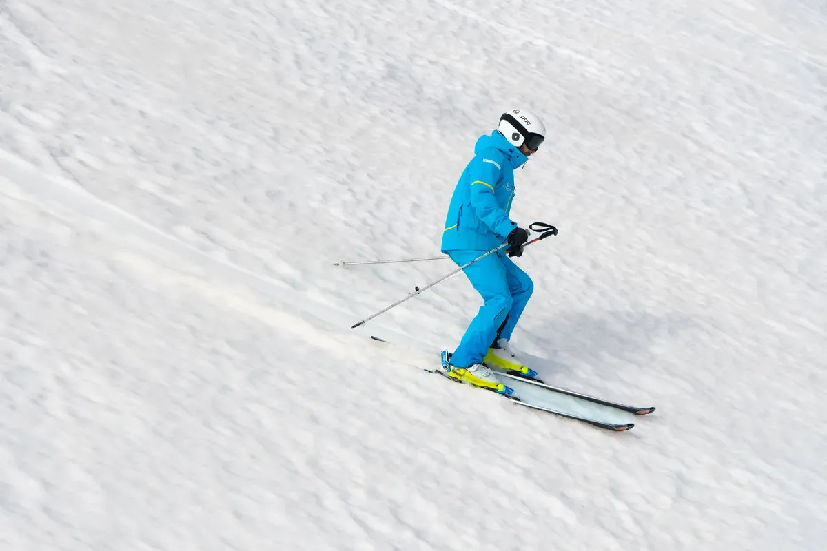 Skier in a blue suit descending a snowy slope