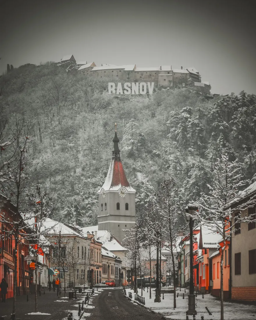 A snowy street in Râșnov with the fortress on the hill above