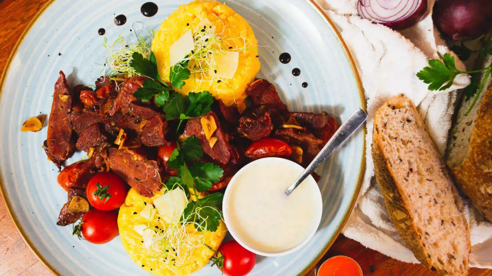 Un plato tradicional rumano con mămăligă, carne frita, tomates, nata agria y pan