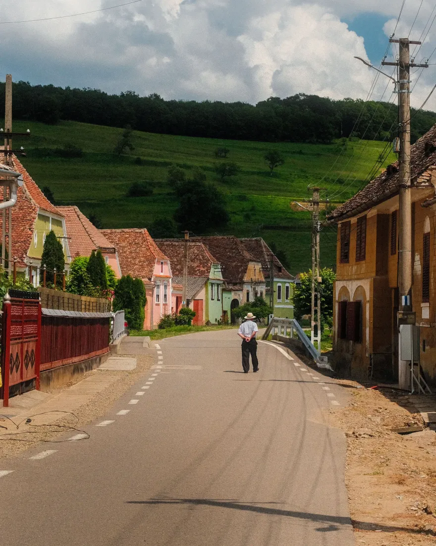 A quiet road through a Romanian village with traditional houses and green hills