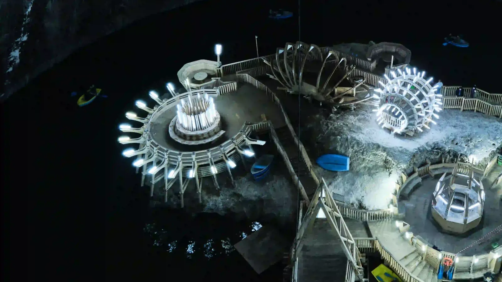 The illuminated underground lake, Ferris wheel and wooden structures inside Salina Turda salt mine