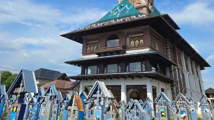 The colourful painted wooden crosses of the Merry Cemetery in Săpânța, with the village church behind