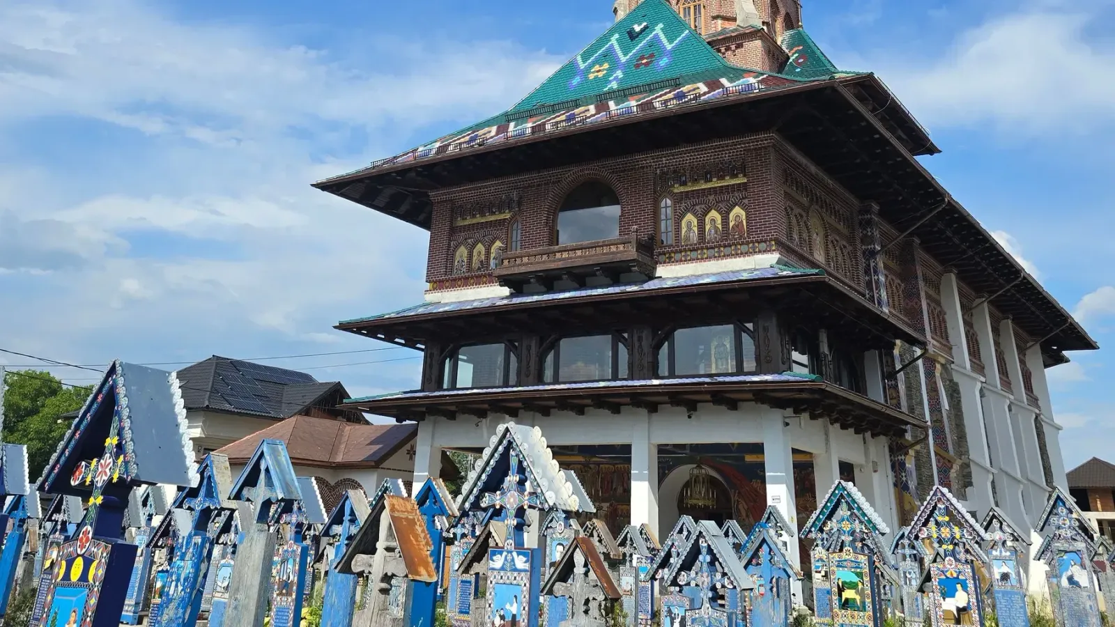 The colourful painted wooden crosses of the Merry Cemetery in Săpânța, with the village church behind