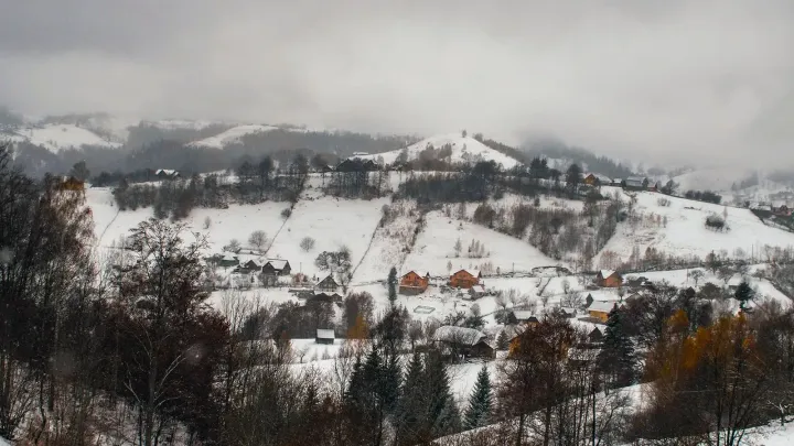 Colinas nevadas y una aldea de montaña en los Cárpatos rumanos en invierno