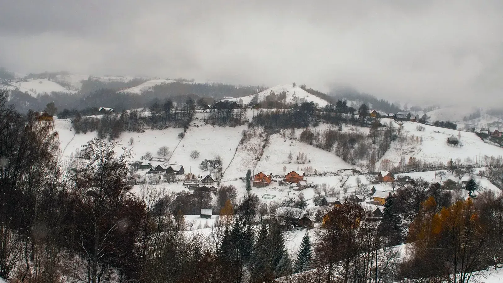 Snow-covered hills and a mountain village in the Romanian Carpathians in winter