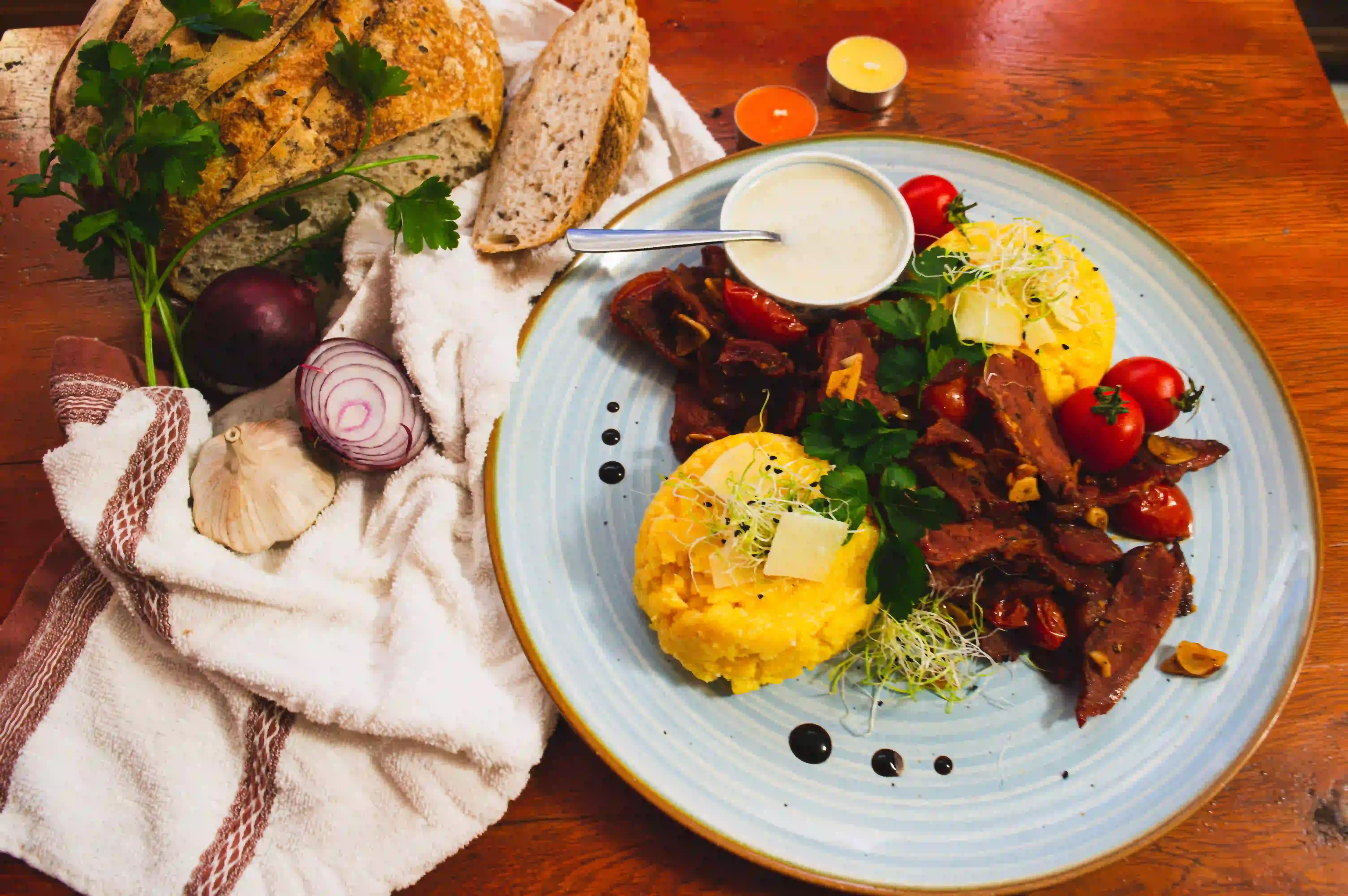 Plate of Romanian food with grilled meat, polenta and sour cream