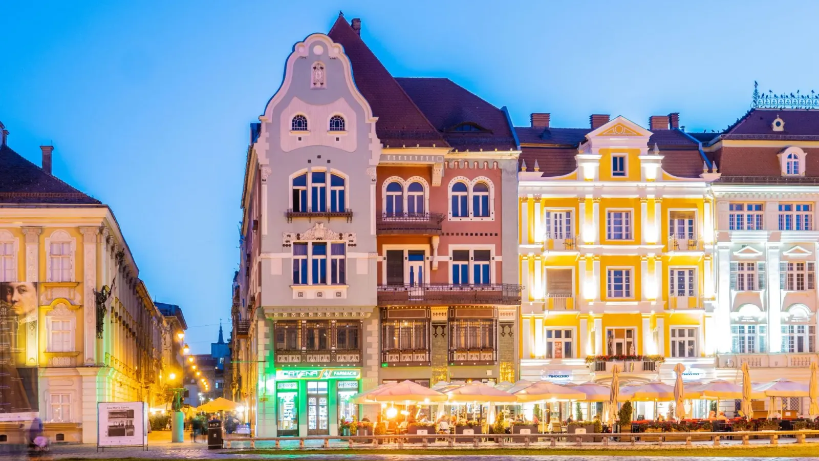 The colourful Secession and Baroque facades of Union Square in Timișoara lit up at dusk