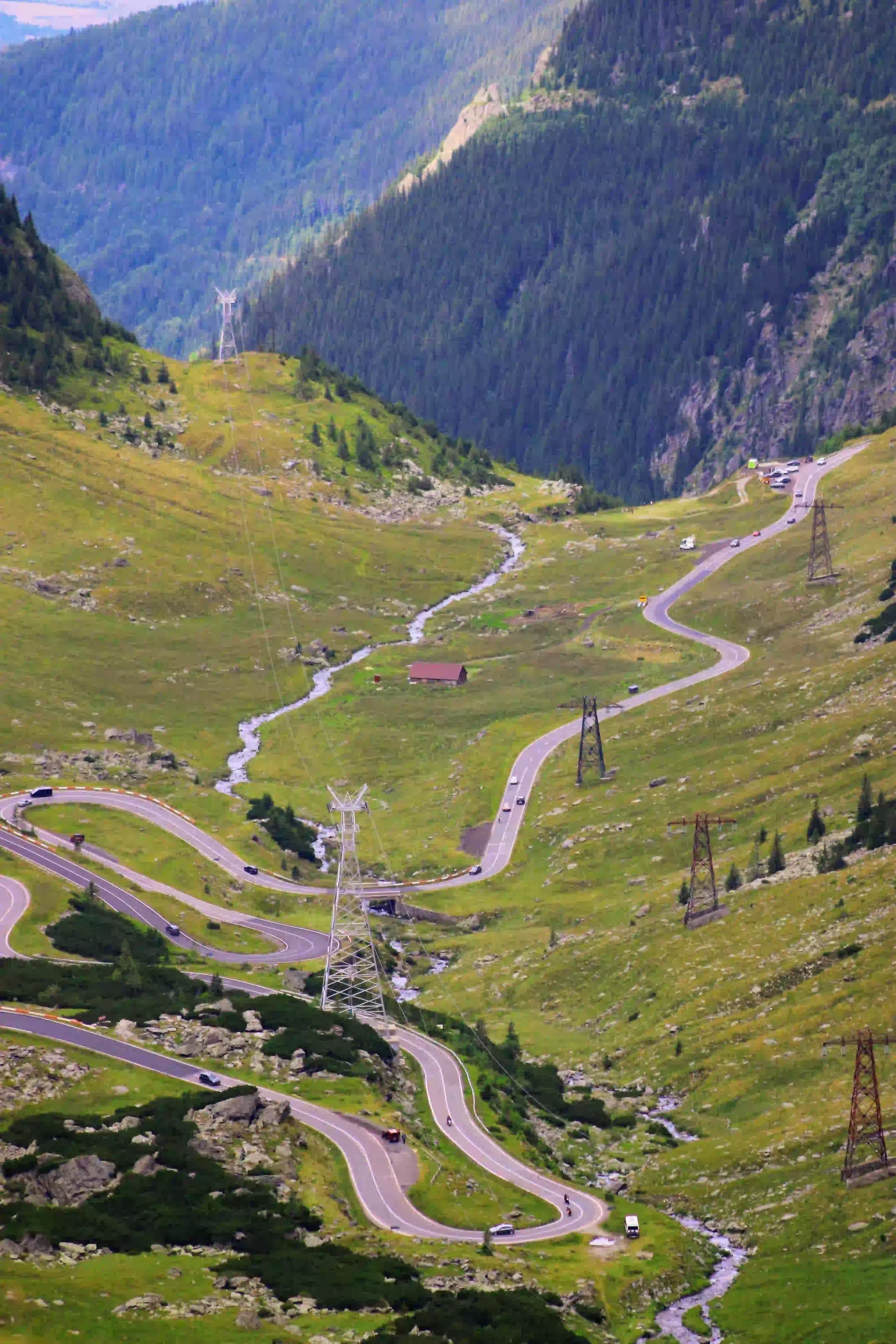 The Transfăgărășan road winding through a green valley in the Făgăraș Mountains