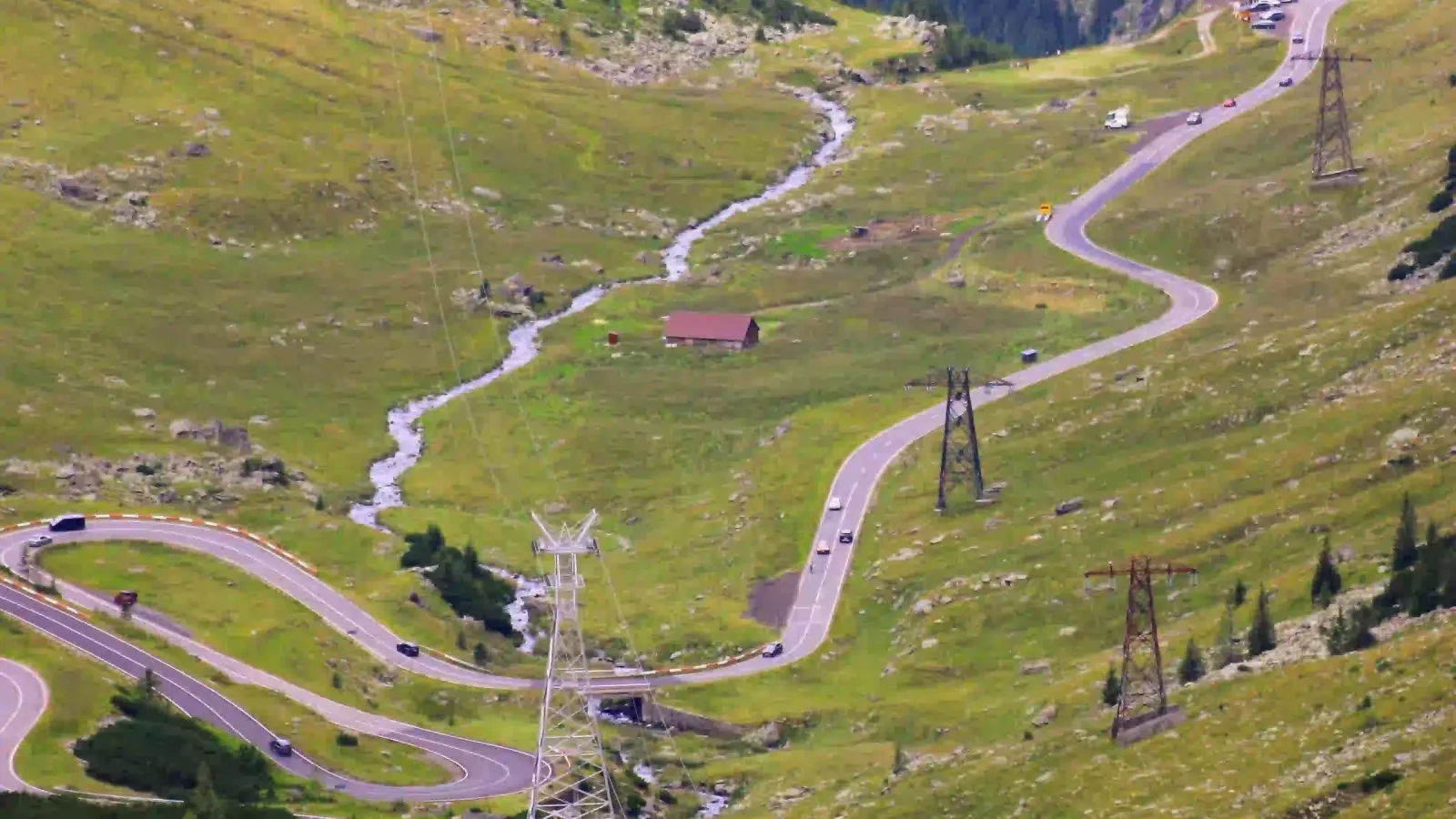 The winding Transfăgărășan road climbing through green mountain meadows